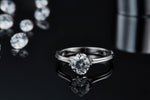 CARISSIE round moissanite solitaire ring, reflection on black surface emphasizing the modern split shank design