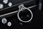 CARISSIE round moissanite solitaire ring, close-up with tweezers focusing on the gallery rail and stone clarity
