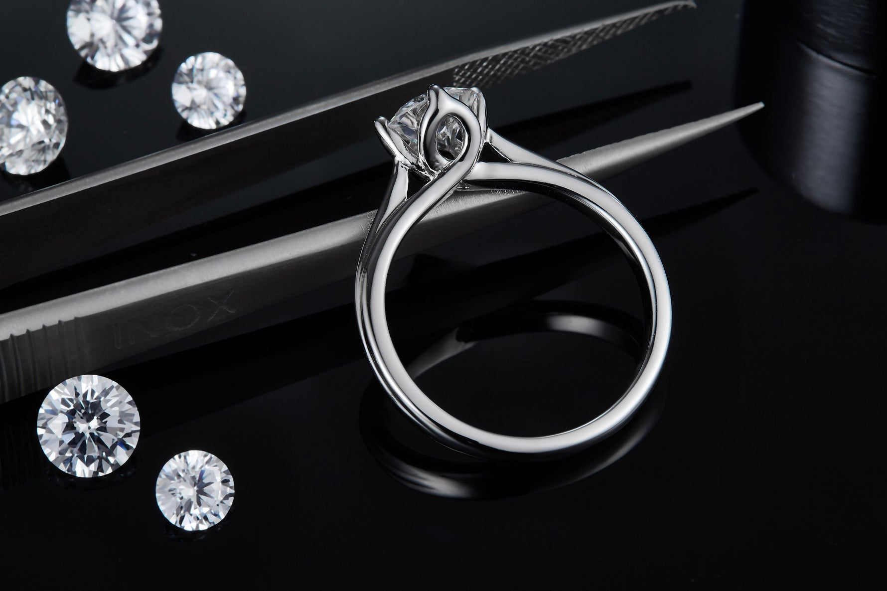 CARISSIE round moissanite solitaire ring, close-up with tweezers focusing on the gallery rail and stone clarity