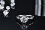 CARISSIE round moissanite halo engagement ring, front view resting on reflective black surface with clear mirror-like reflection