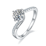 CARISSIE round moissanite solitaire ring, angled view highlighting the split shank band with pavé stones and polished silver metal