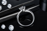 CARISSIE round moissanite solitaire ring, resting on tweezers to display the inner band structure and side-set stones