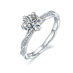 CARISSIE round moissanite solitaire ring, angled view showcasing the wavy silver band and pavé leaf accents