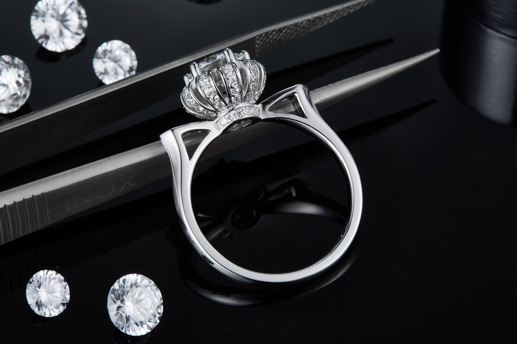 CARISSIE round moissanite halo ring, macro detail resting on tweezers revealing the intricate vertical prong setting