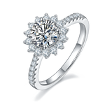CARISSIE round moissanite halo engagement ring, angled view highlighting the flower-like halo and pavé band in white metal.