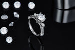 CARISSIE round moissanite solitaire ring, lifestyle shot on black background with loose stones showcasing side sparkle