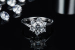 CARISSIE round moissanite cluster ring, front view with reflection on glossy background showcasing stone brilliance