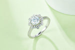 CARISSIE round moissanite halo ring, lifestyle shot on a soft green background emphasizing the center stone brilliance