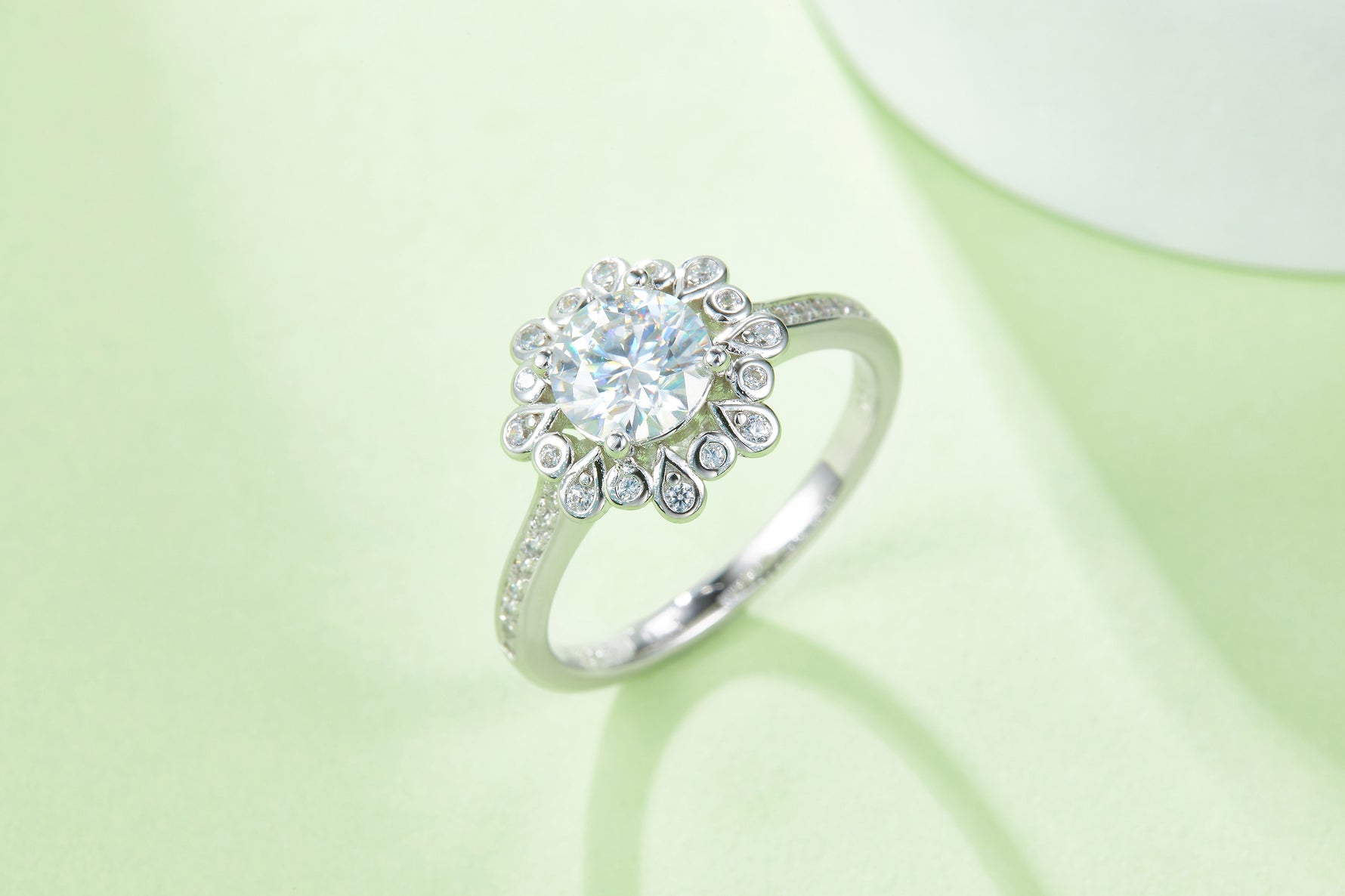 CARISSIE round moissanite halo ring, lifestyle shot on a soft green background emphasizing the center stone brilliance