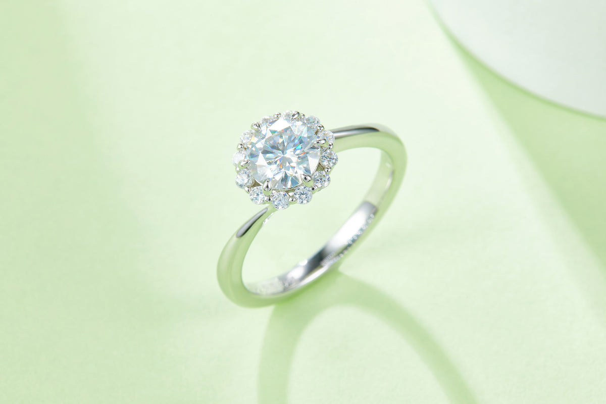 CARISSIE round moissanite halo engagement ring, artistic lifestyle shot on a soft green background highlighting stone sparkle