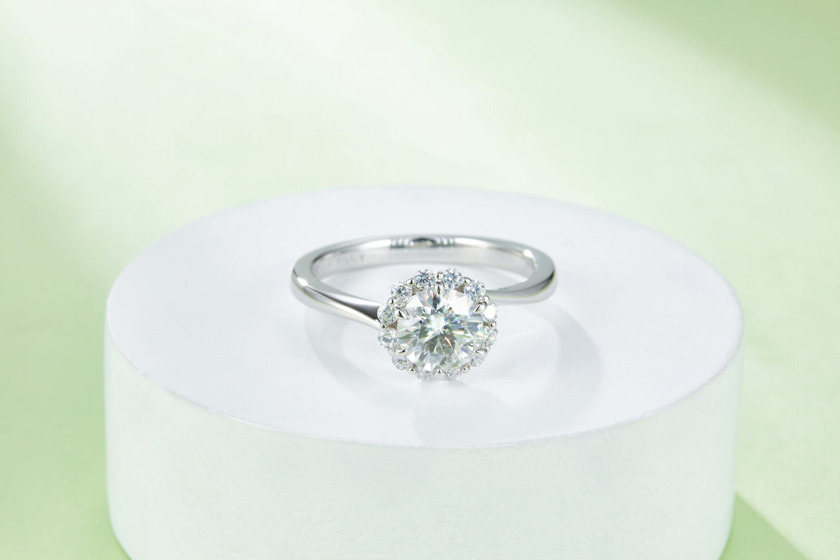 CARISSIE round moissanite halo engagement ring, elevated view on a white pedestal showcasing the prong setting details