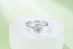 CARISSIE round moissanite halo engagement ring, elevated view on a white pedestal showcasing the prong setting details