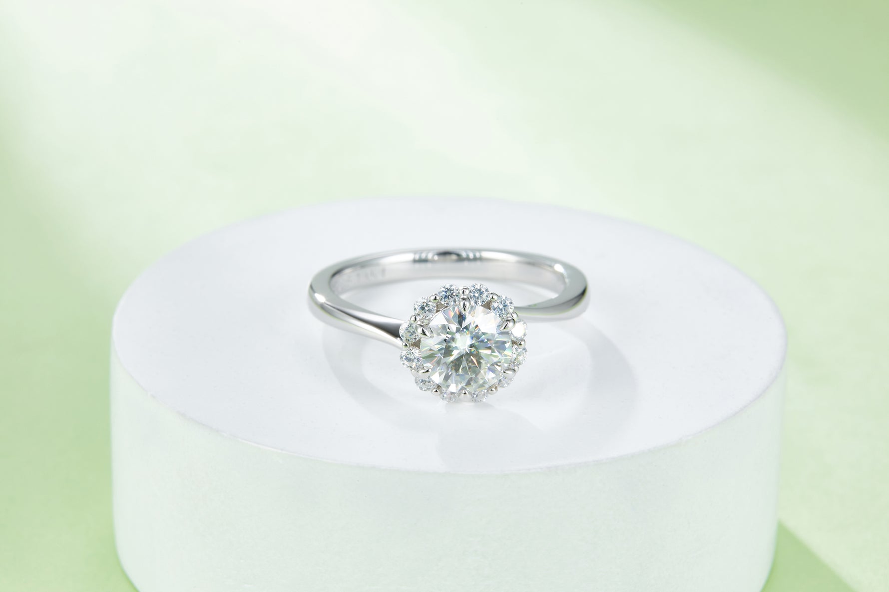 CARISSIE round moissanite halo engagement ring, elevated view on a white pedestal showcasing the prong setting details