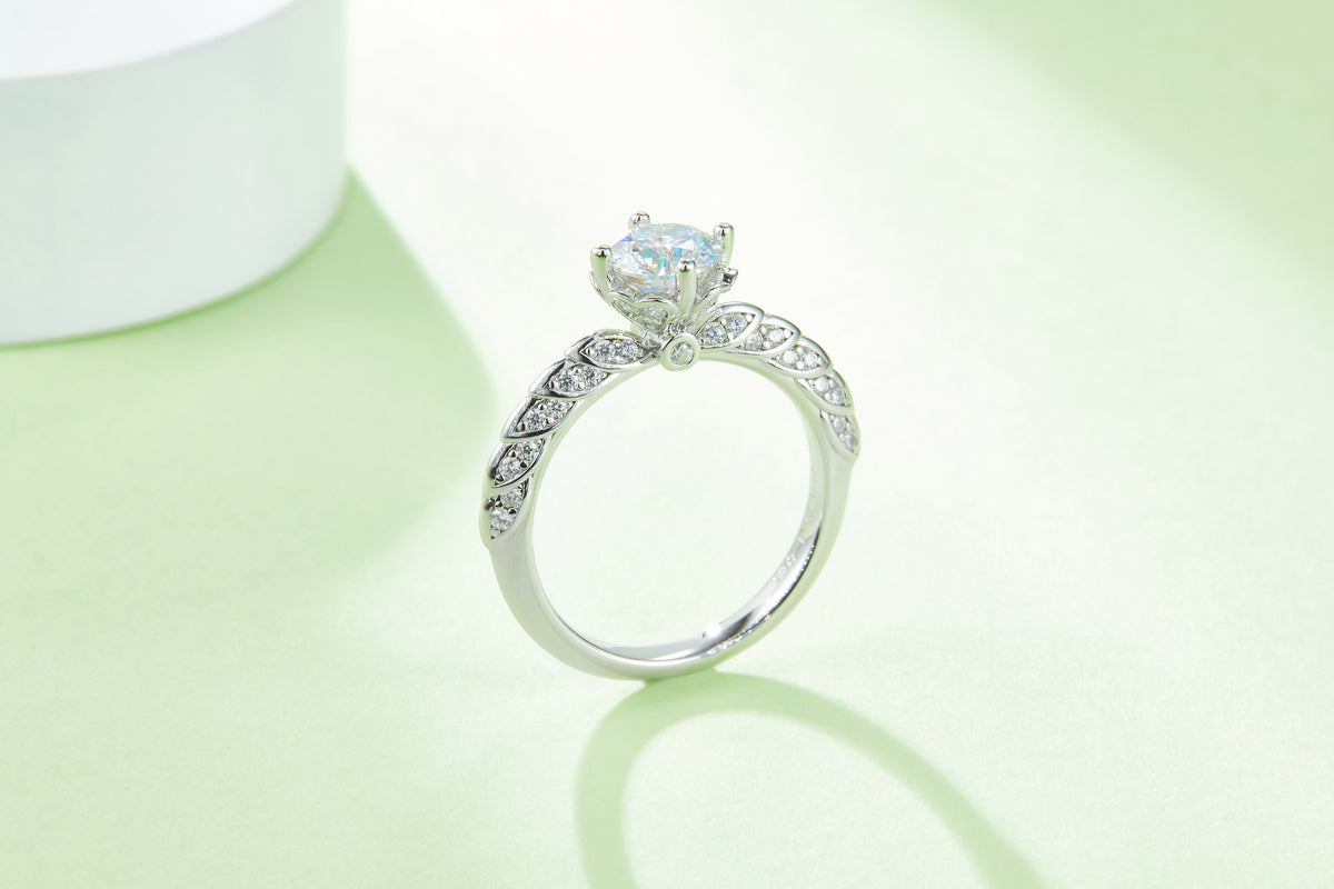 CARISSIE round moissanite solitaire ring, profile view against a soft green backdrop revealing the elegant curve of the shank
