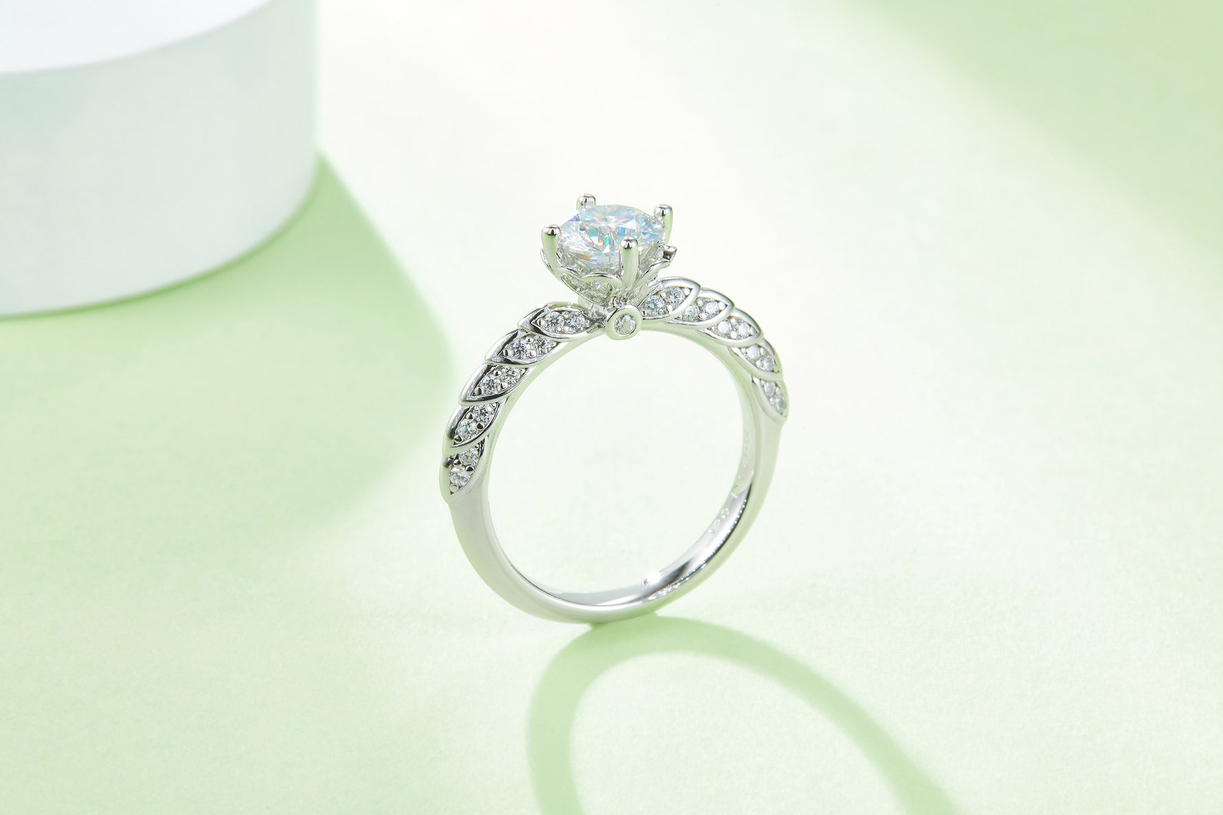CARISSIE round moissanite solitaire ring, profile view against a soft green backdrop revealing the elegant curve of the shank