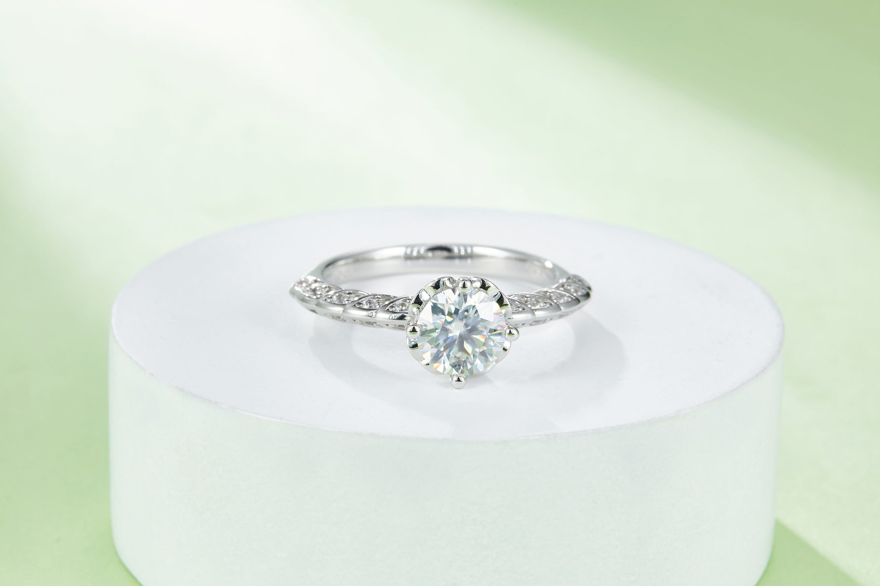 CARISSIE round moissanite solitaire ring, centered view on a white pedestal emphasizing the symmetrical band design