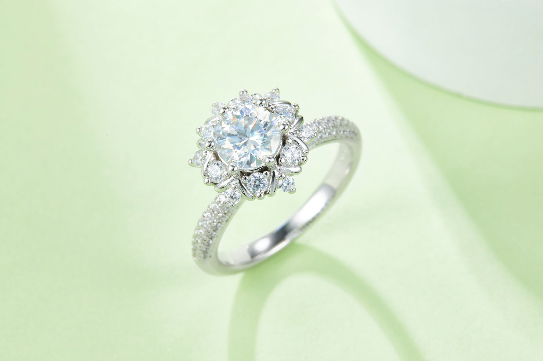 CARISSIE round moissanite cluster engagement ring, lifestyle shot on soft green background emphasizing brilliance