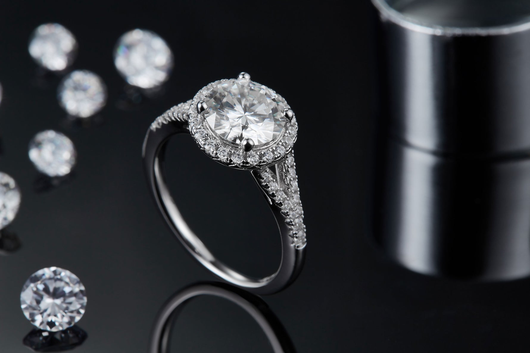 CARISSIE round moissanite halo ring, lifestyle shot with dark background emphasizing the sparkle of the white metal setting