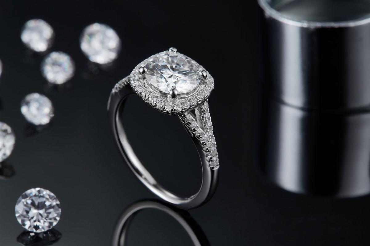 CARISSIE round moissanite halo engagement ring, artistic lifestyle shot on dark background with scattered loose gemstones