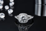 CARISSIE round moissanite halo engagement ring, front perspective on reflective surface emphasizing brilliant center stone sparkle