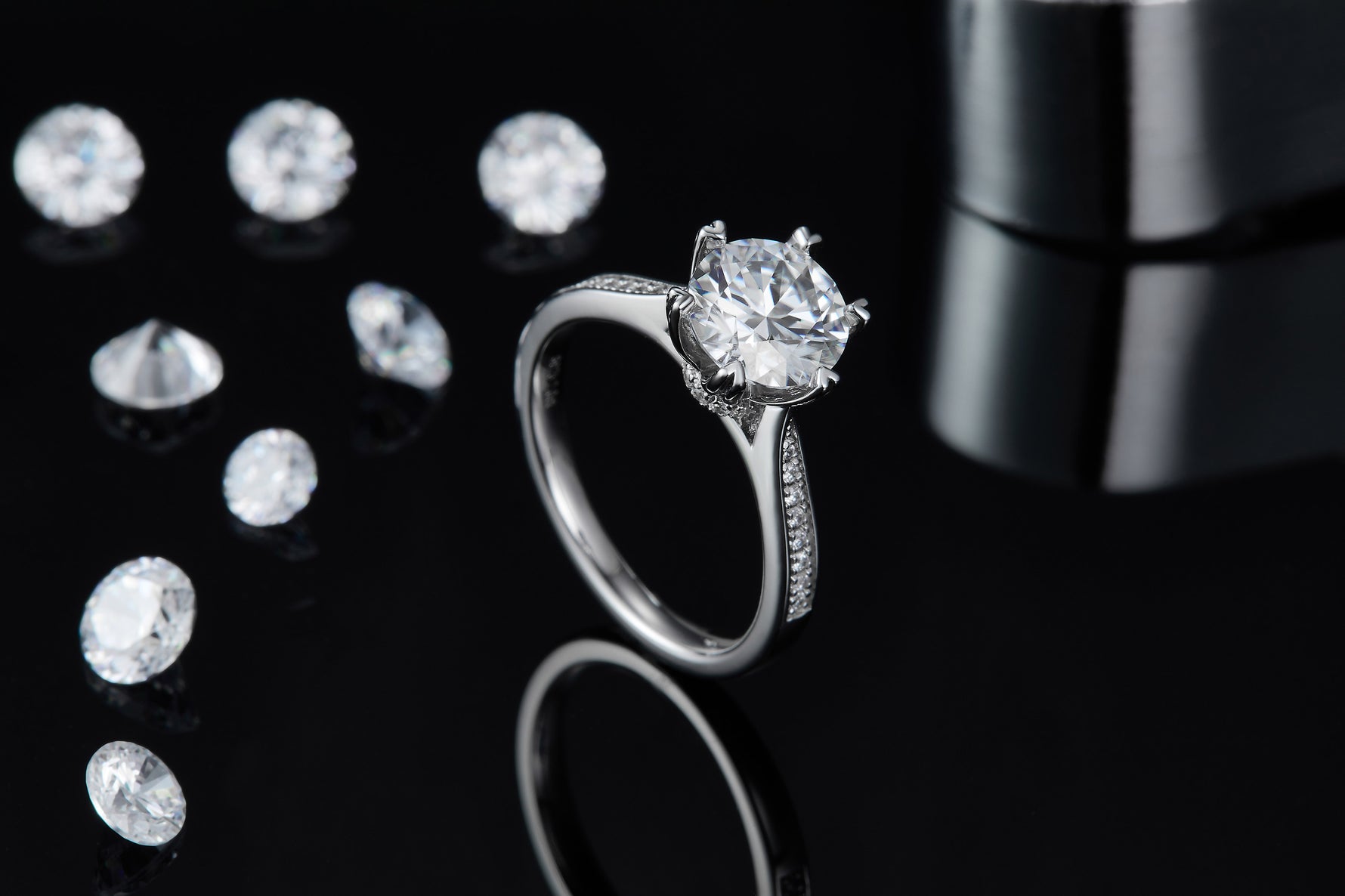 CARISSIE round moissanite solitaire ring, lifestyle shot on black background displaying elegant curve of the shank and sparkle
