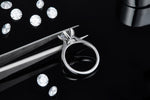 CARISSIE round moissanite solitaire ring, held by tweezers to showcase craftsmanship details of the prongs and gallery rail