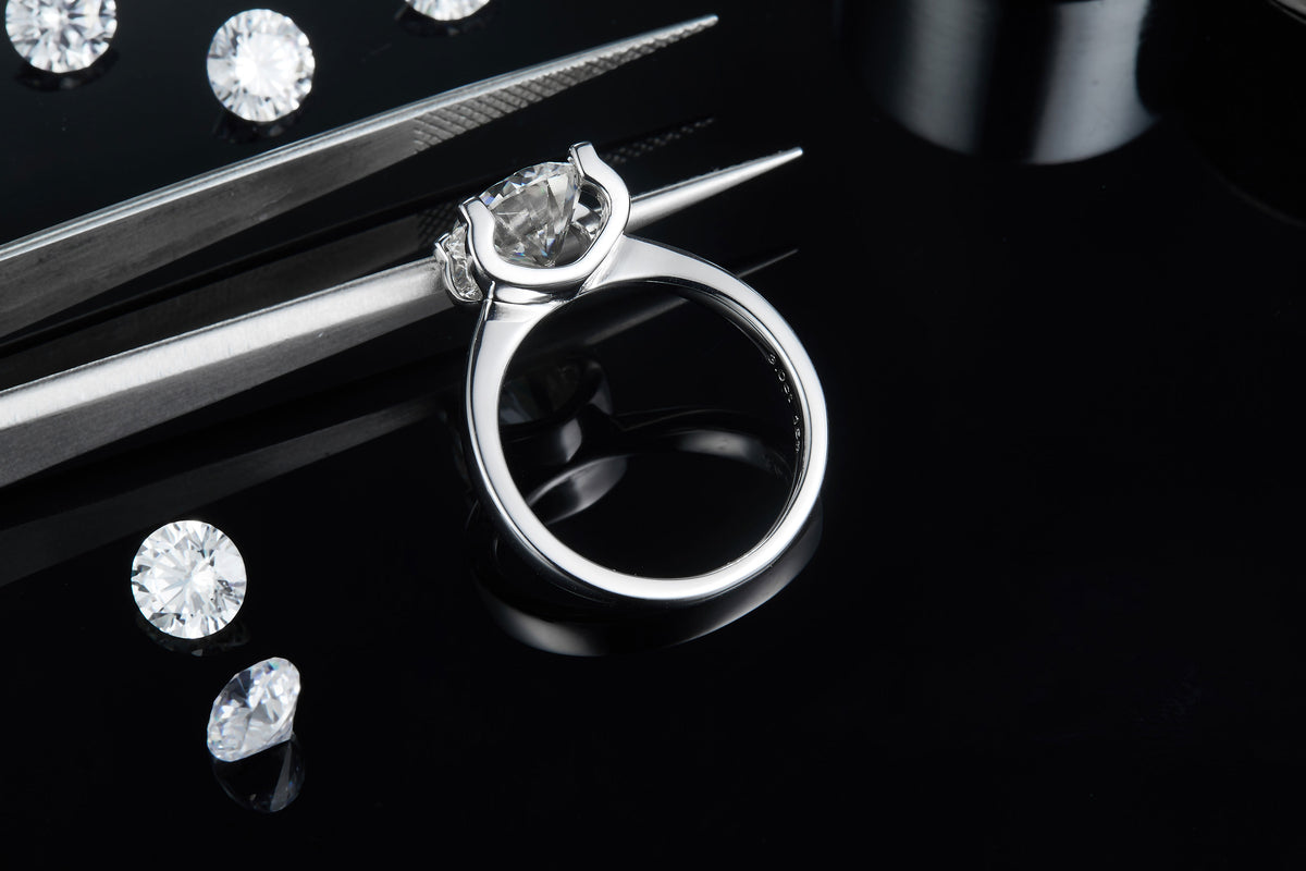 CARISSIE round moissanite solitaire ring, resting on tweezers to show the profile height and sleek metal craftsmanship