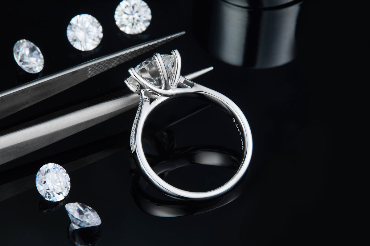 CARISSIE round moissanite solitaire ring, detailed angle showing craftsmanship near tweezers and interior hallmarks