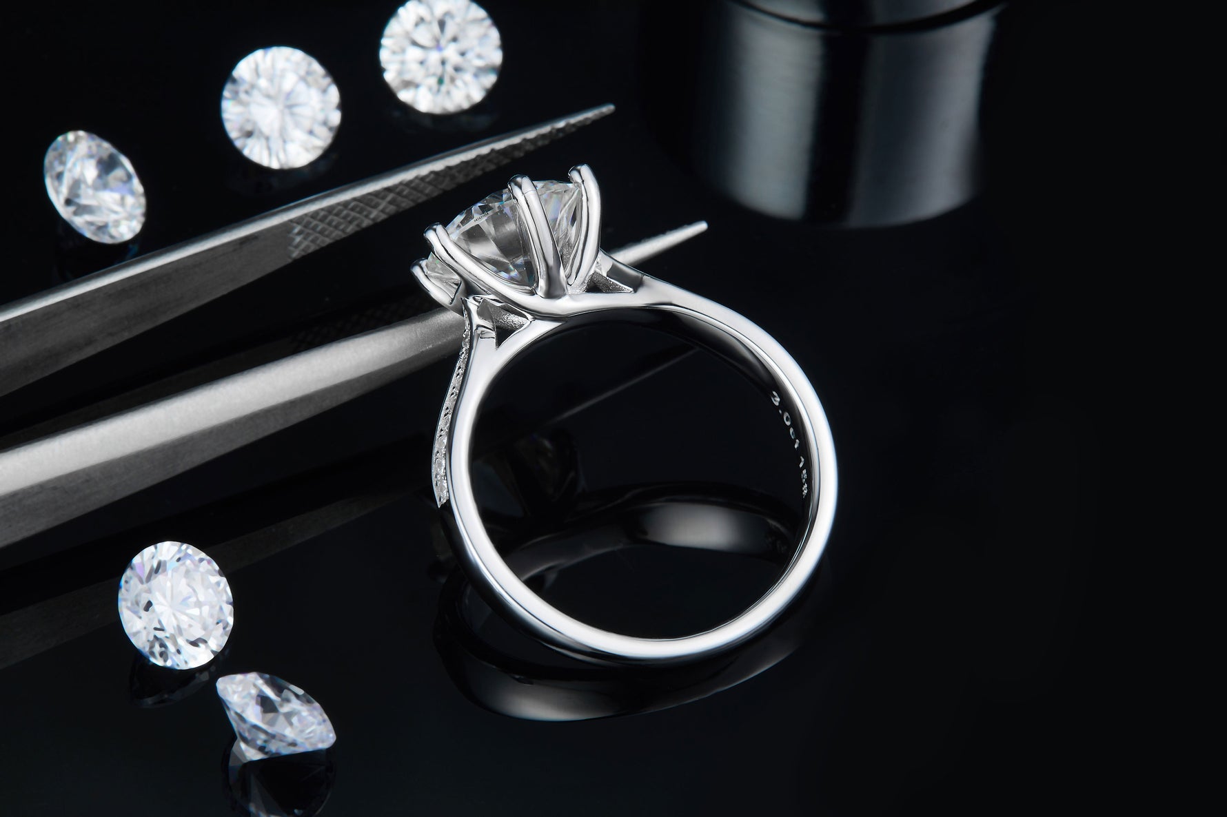 CARISSIE round moissanite solitaire ring, detailed angle showing craftsmanship near tweezers and interior hallmarks