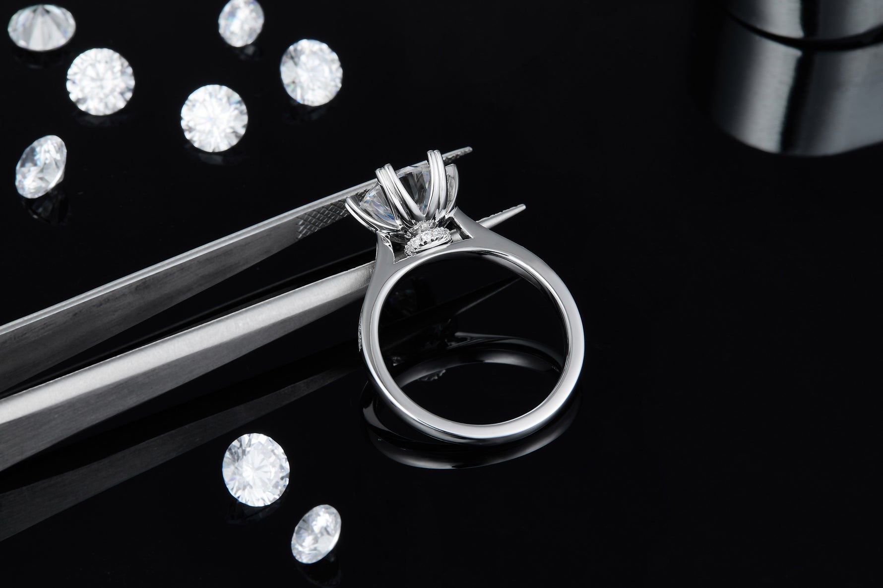 CARISSIE round moissanite jewelry ring, close-up held by tweezers revealing the polished interior of the silver band