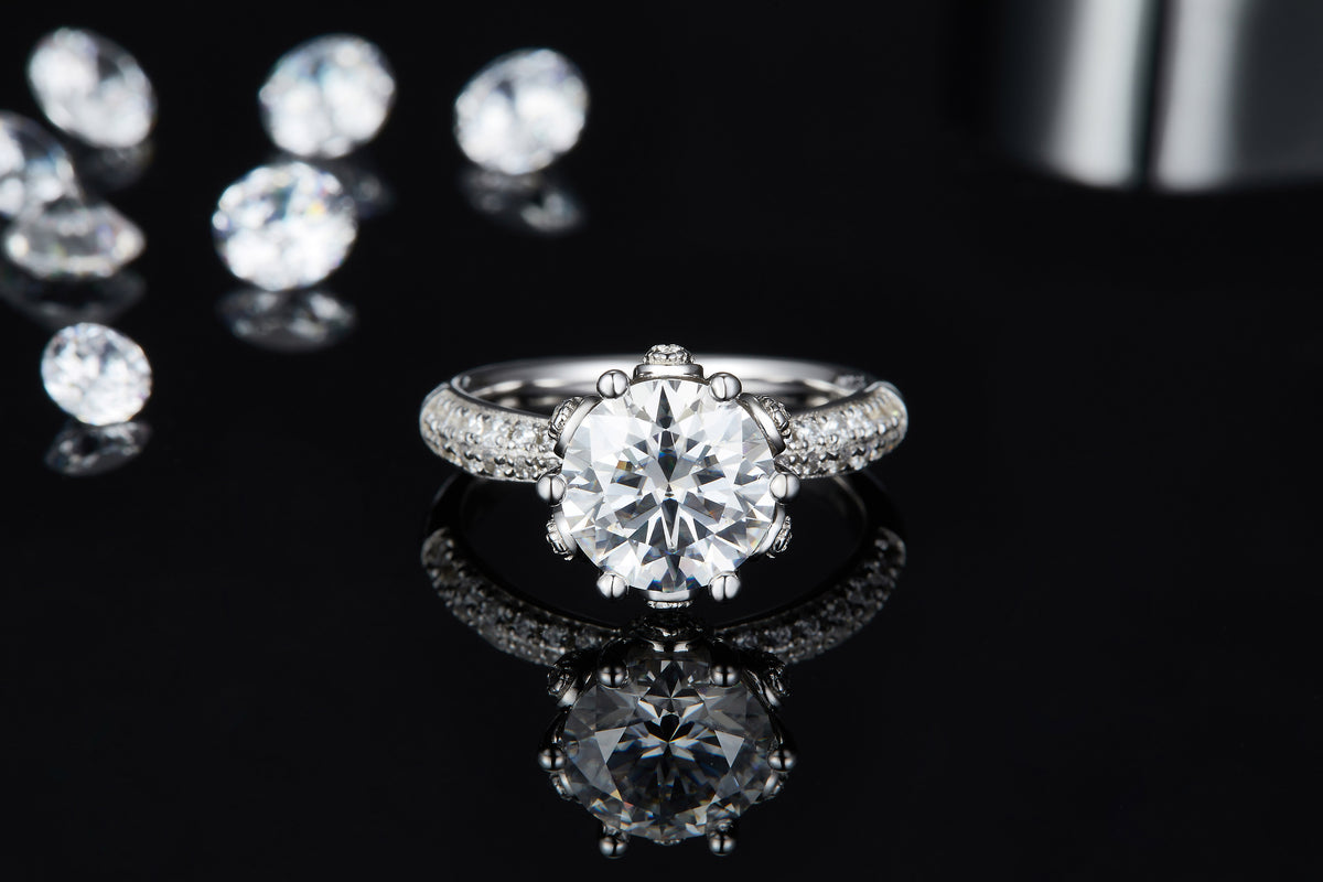 CARISSIE round moissanite engagement ring, top-down perspective on glossy black background showing clear reflection