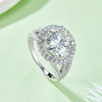 CARISSIE round moissanite halo engagement ring, lifestyle shot on a soft green background displaying brilliant fire in the stones