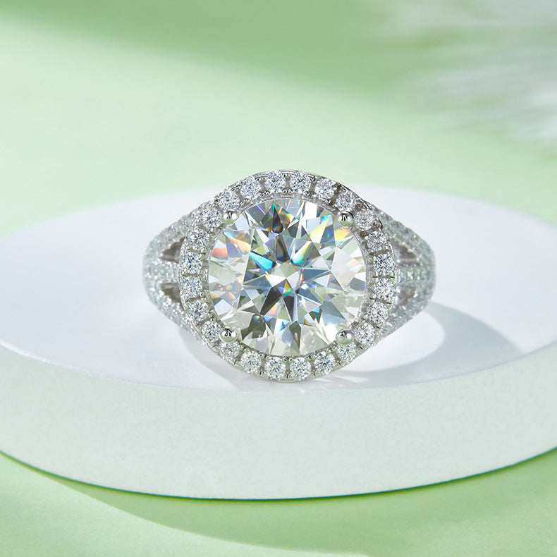 CARISSIE round moissanite halo engagement ring, displayed on a white pedestal to emphasize the sparkle of the silver-tone setting