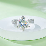 CARISSIE round moissanite engagement ring, styled shot on white display showing rainbow fire within the large center stone