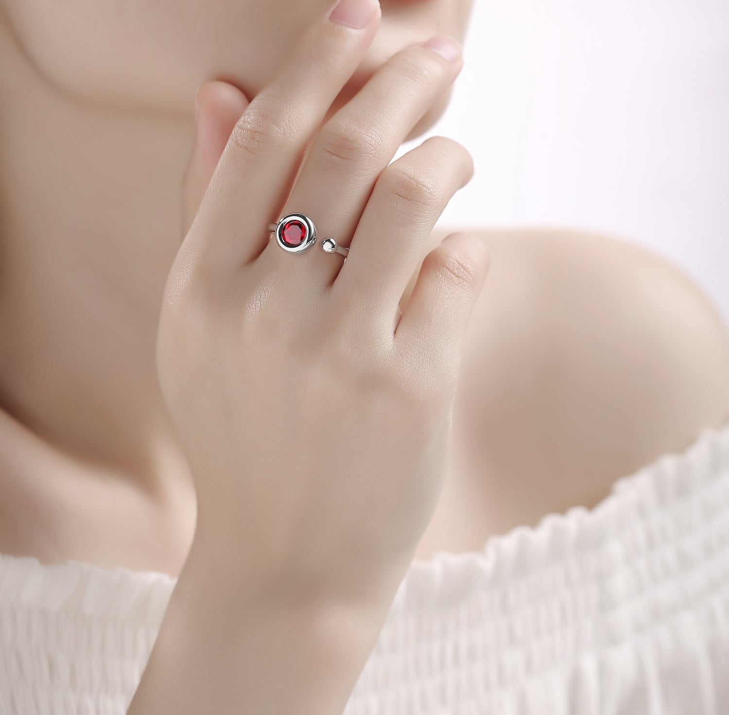 CARISSIE round moissanite bezel ring, model wearing red gemstone version with open-ended adjustable design