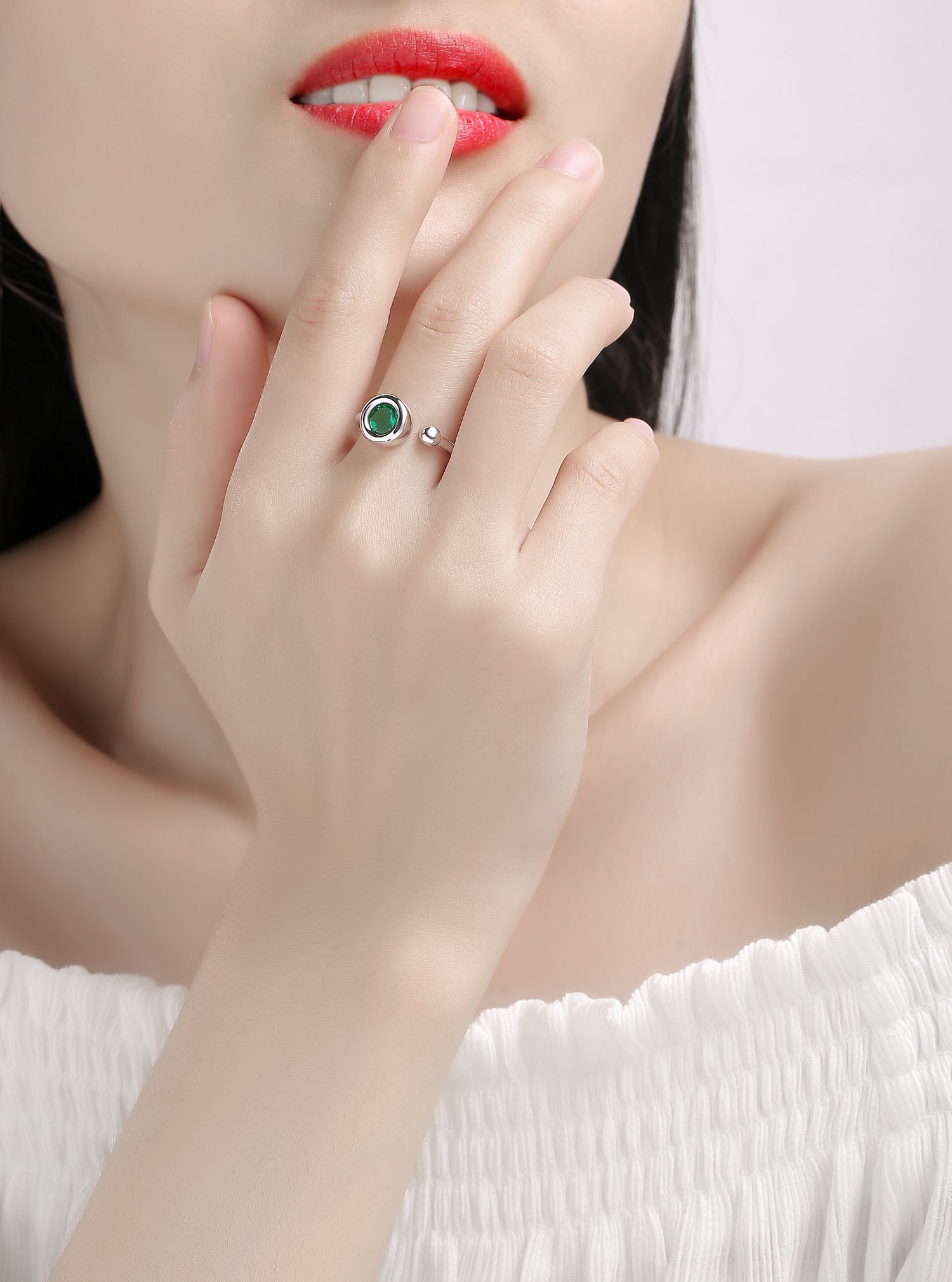 CARISSIE round moissanite bezel ring, lifestyle shot on model hand with green stone and polished silver band