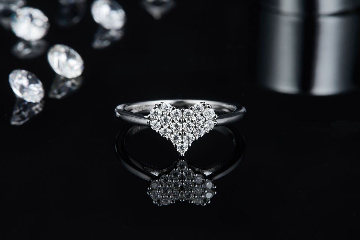 CARISSIE heart-shaped moissanite ring, front view on reflective dark surface displaying brilliant sparkle