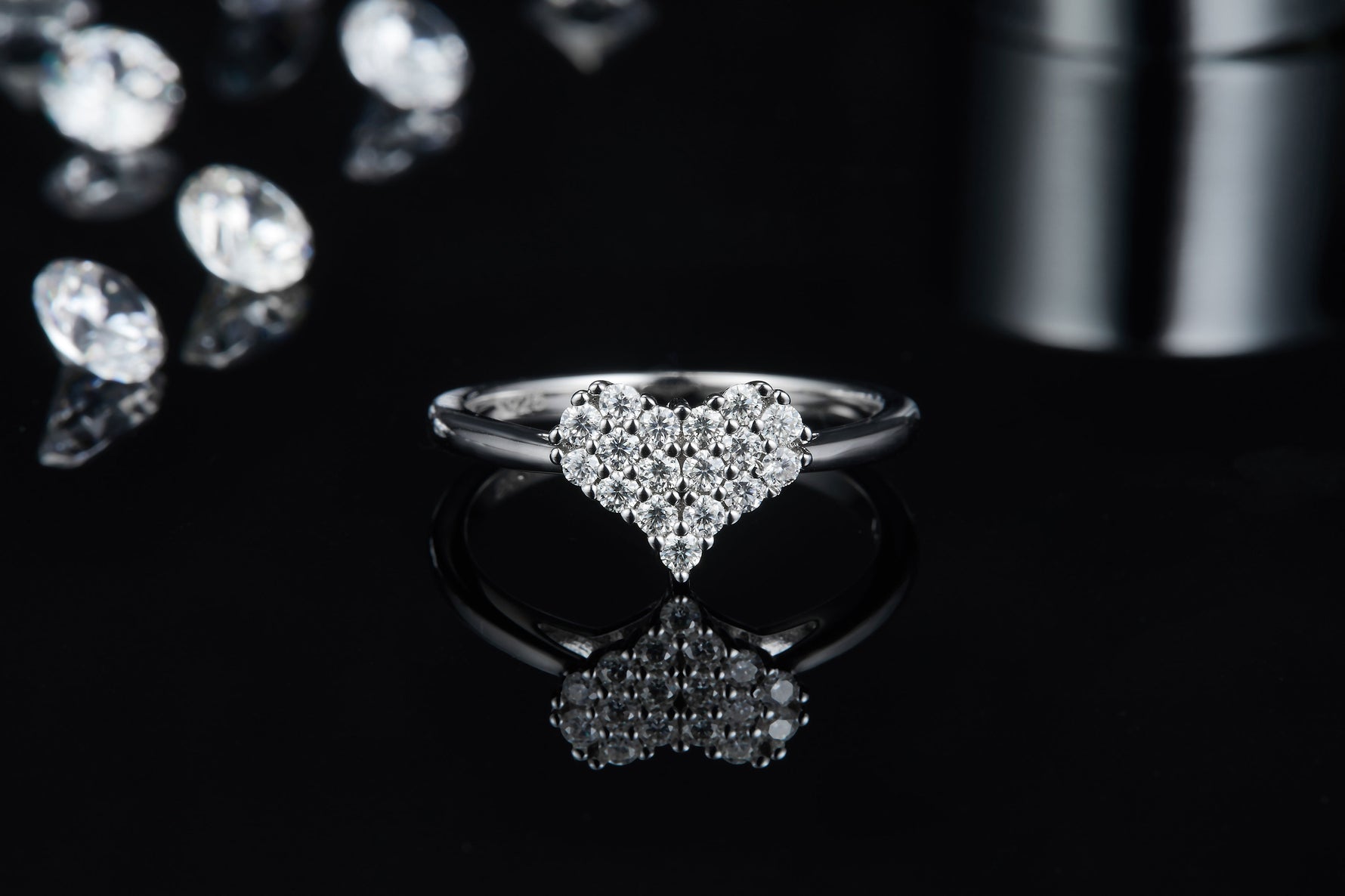 CARISSIE heart-shaped moissanite ring, front view on reflective dark surface displaying brilliant sparkle