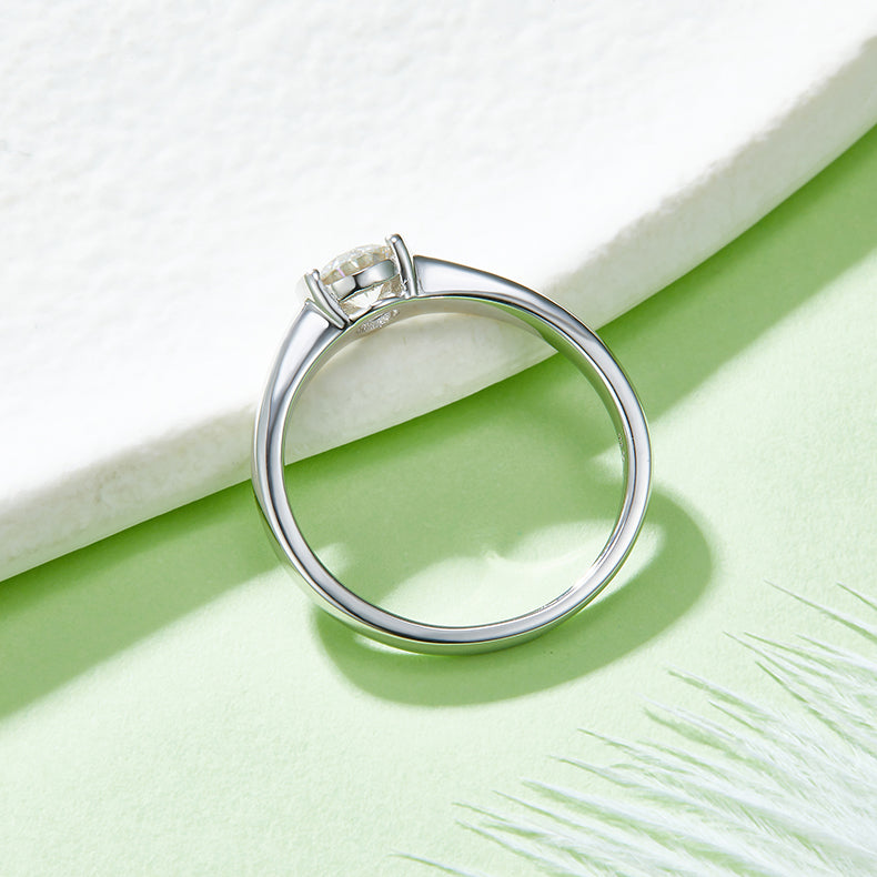 CARISSIE round moissanite bezel ring, diagonal angle resting against a white block to show the interior of the band