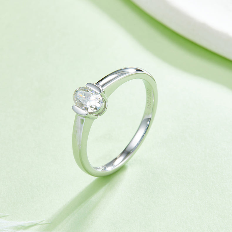 CARISSIE oval moissanite bezel ring, side angle on green background displaying the interior metal stamping