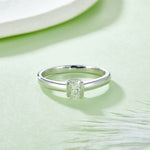 CARISSIE emerald cut bezel engagement ring, top-down perspective on a green surface emphasizing the clean lines of the bezel