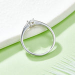 CARISSIE emerald cut bezel engagement ring, side angle against a white block showcasing the tapered band and secure setting