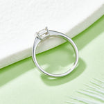CARISSIE Asscher bezel engagement ring, side angle resting on a textured surface revealing the tapered shank.