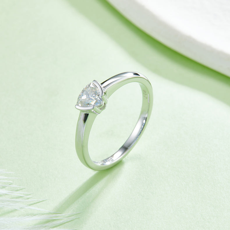 CARISSIE trillion moissanite bezel ring, lifestyle shot on a green surface showing the polished finish and facets