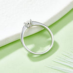 CARISSIE pear moissanite bezel engagement ring, side profile on green background emphasizing the low-profile bezel height