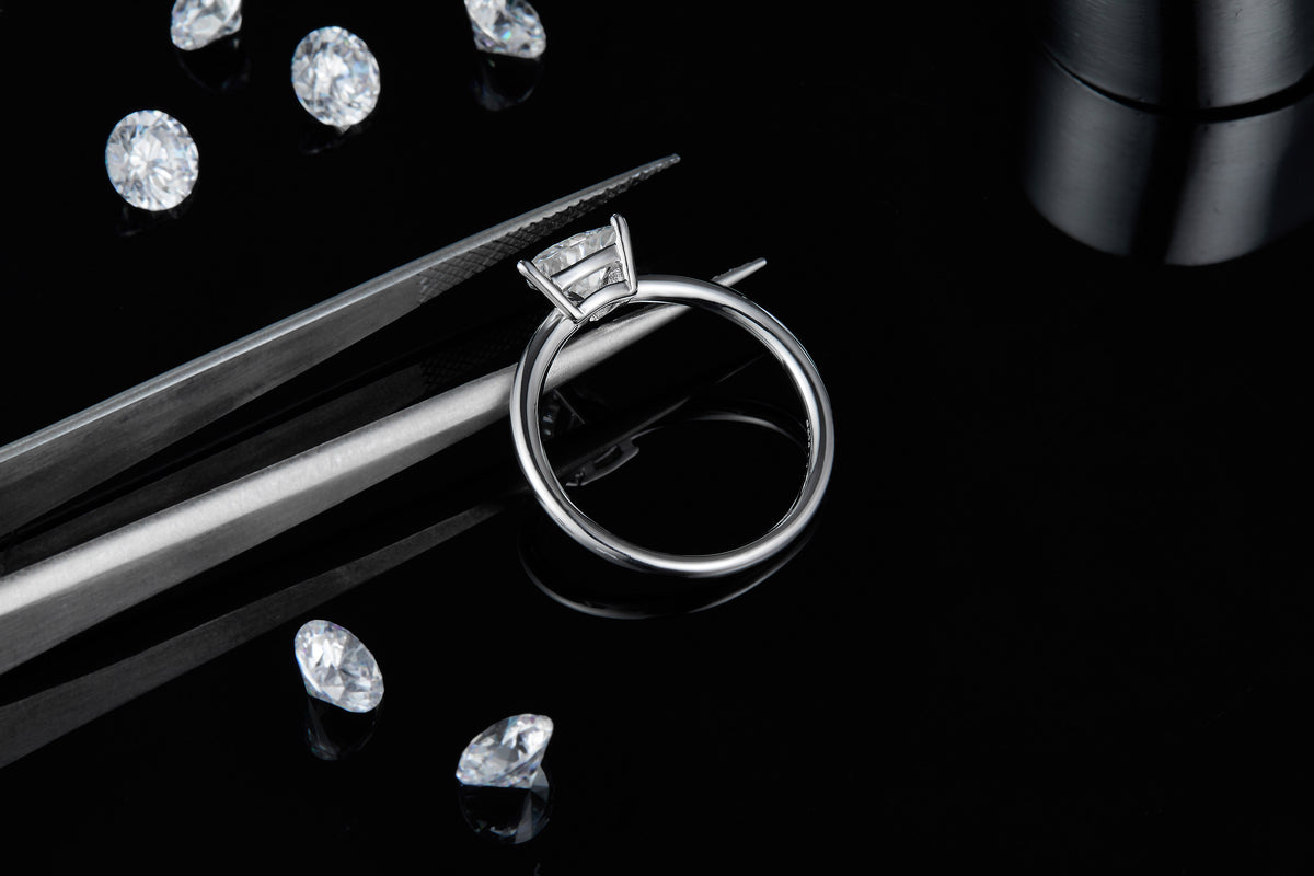 CARISSIE trillion solitaire ring, side profile on black background with tweezers emphasizing the elevated stone height
