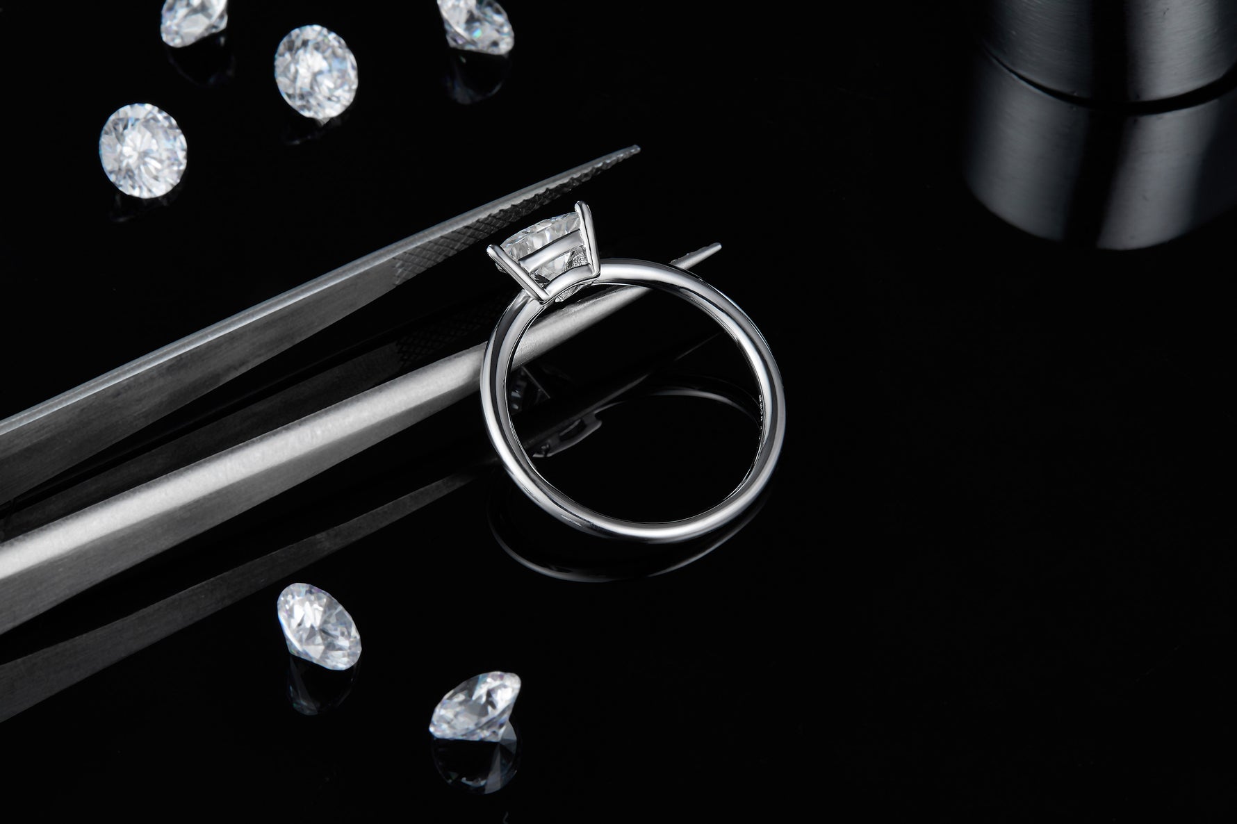 CARISSIE trillion solitaire ring, side profile on black background with tweezers emphasizing the elevated stone height
