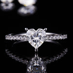 CARISSIE heart solitaire engagement ring, centered close-up on reflective black surface showcasing the sparkle of the heart cut stone