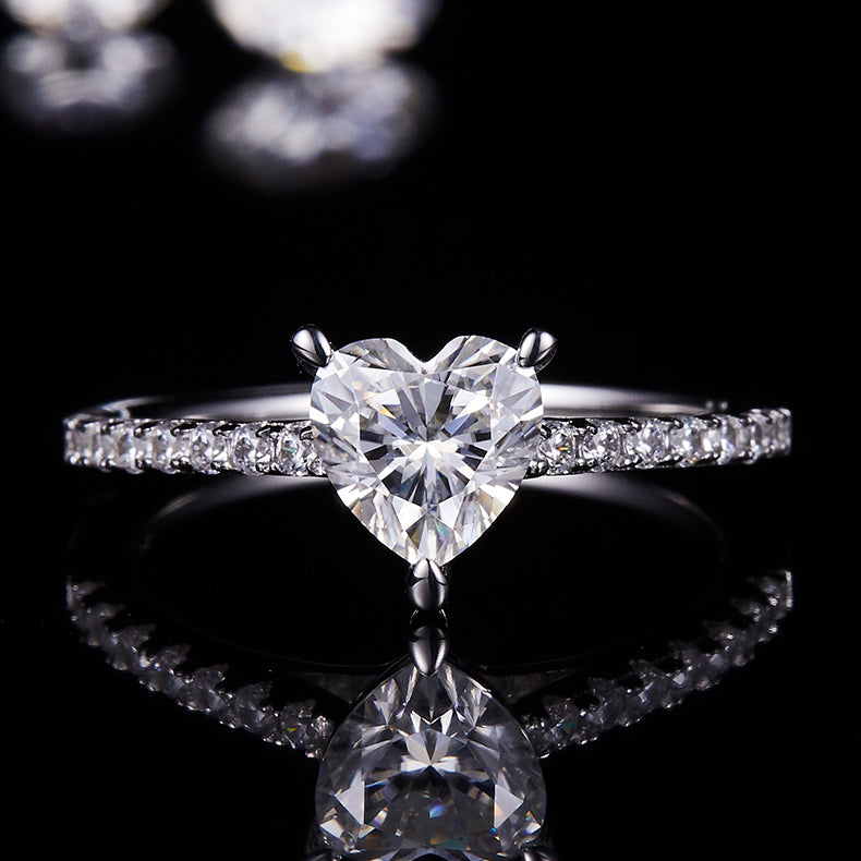 CARISSIE heart solitaire engagement ring, centered close-up on reflective black surface showcasing the sparkle of the heart cut stone