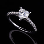 CARISSIE heart solitaire engagement ring, dramatic dark background shot emphasizing the brilliance of the moissanite and silver metal